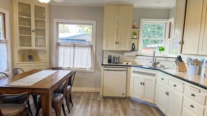 Una cocina con armarios de madera, una mesa de comedor con sillas y una ventana con vistas al exterior.
