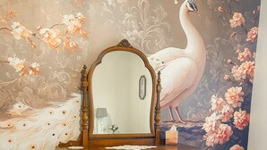 Un dormitorio con tocador, espejo, silla y colcha con estampado floral.