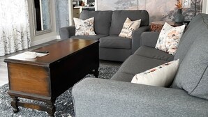 Una sala de estar con un sofá gris, una mesa de centro de madera y una alfombra estampada.