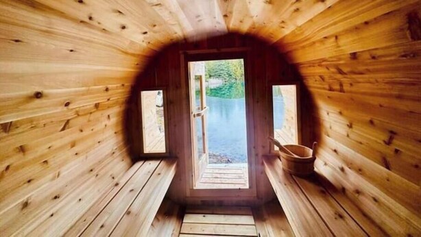 A wooden cabin with a circular entrance, two windows, and a wooden bench. - Private Lake with 180° views (Uxbridge)
