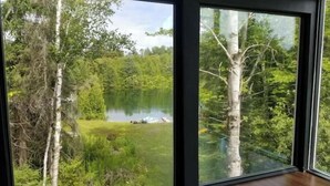 A room with large windows offering a view of a lake surrounded by trees. - Private Lake with 180° views (Uxbridge)