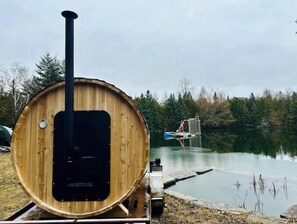 Relax in a sauna or hot tub on a wooden platform overlooking a serene lake.