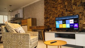 A modern living room with a patterned armchair, a wooden coffee table, and a flat-screen TV displaying streaming apps. - New Apartment City Oasis In Roma Norte (Mexico City)