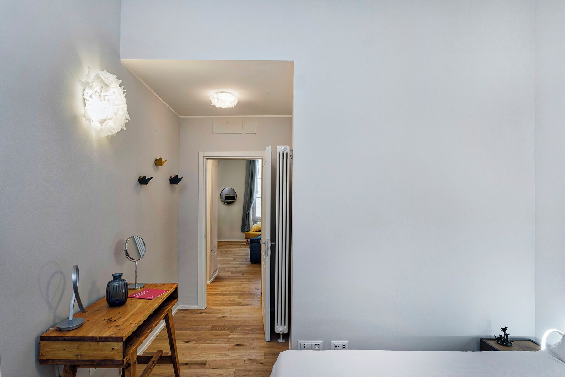 Ein modernes Hotelzimmer mit einem Holztisch, einem Spiegel, einer Vase und einem Bett.