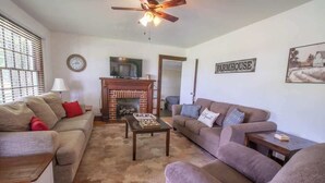 Una sala de estar con chimenea, dos sofás, una mesa de centro y un ventilador de techo.