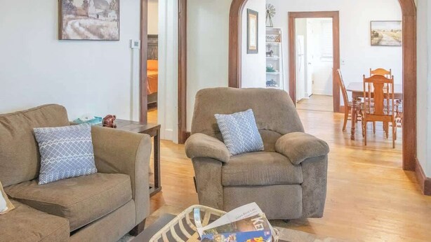 Una sala de estar con dos sofás, una mesa de centro y un comedor con una mesa y sillas de madera.