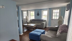 A living room with a sofa, ottoman, coffee table, and a lamp.