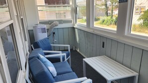 A sunroom with a view of the outdoors, featuring a seating area with blue cushioned chairs and a small table.