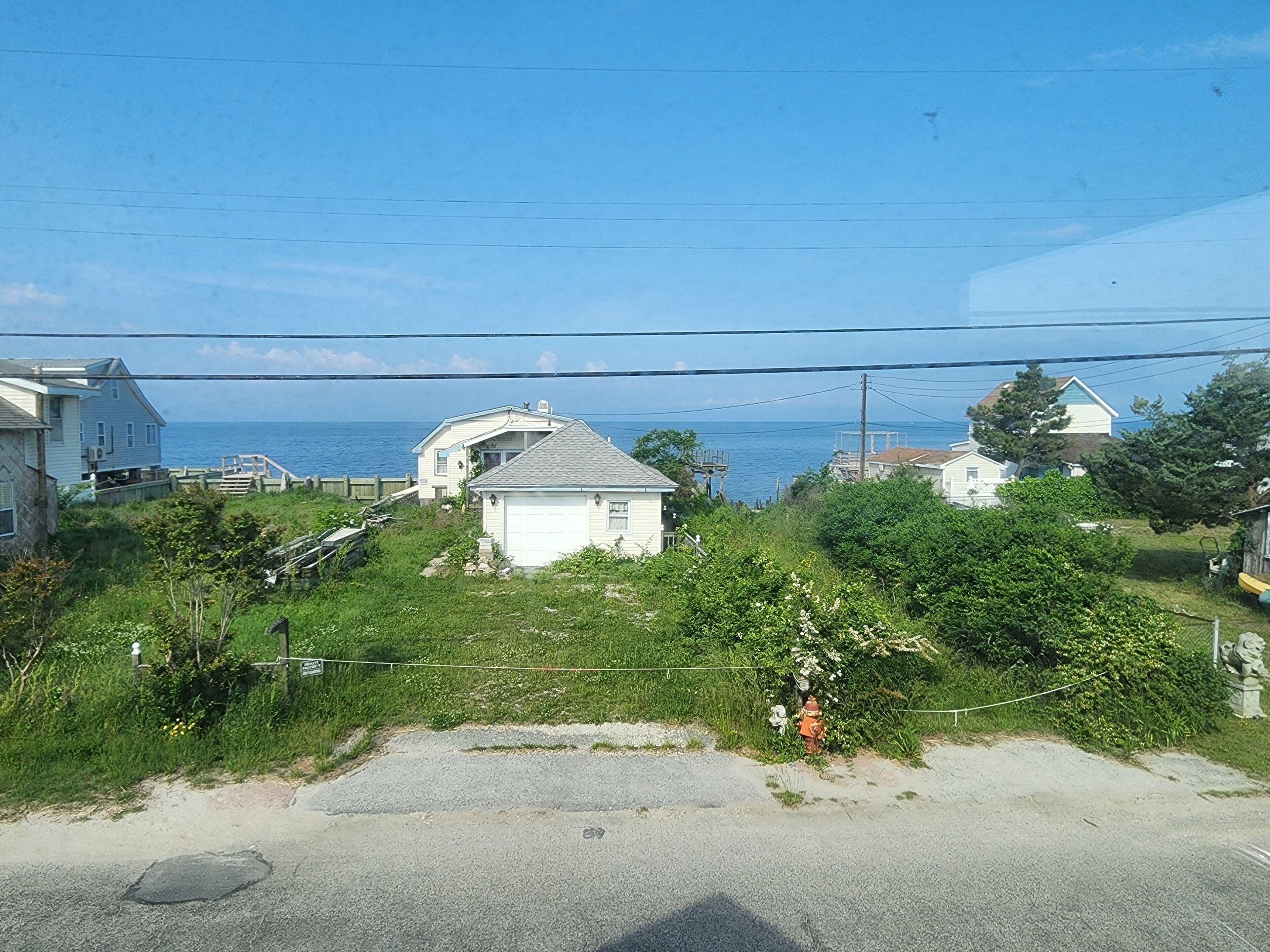 A coastal residential area with houses, a clear sky, and a view of the sea.