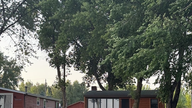 Un chalet au bord du lac, doté d’une jetée, d’un espace salon extérieur et d’un mur en pierre.