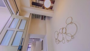 A hallway with a staircase, a wall-mounted light fixture, and a decorative metal piece. - Beautiful double suite in an old house with contemporary restoration.  (Heroica Puebla de Zaragoza)