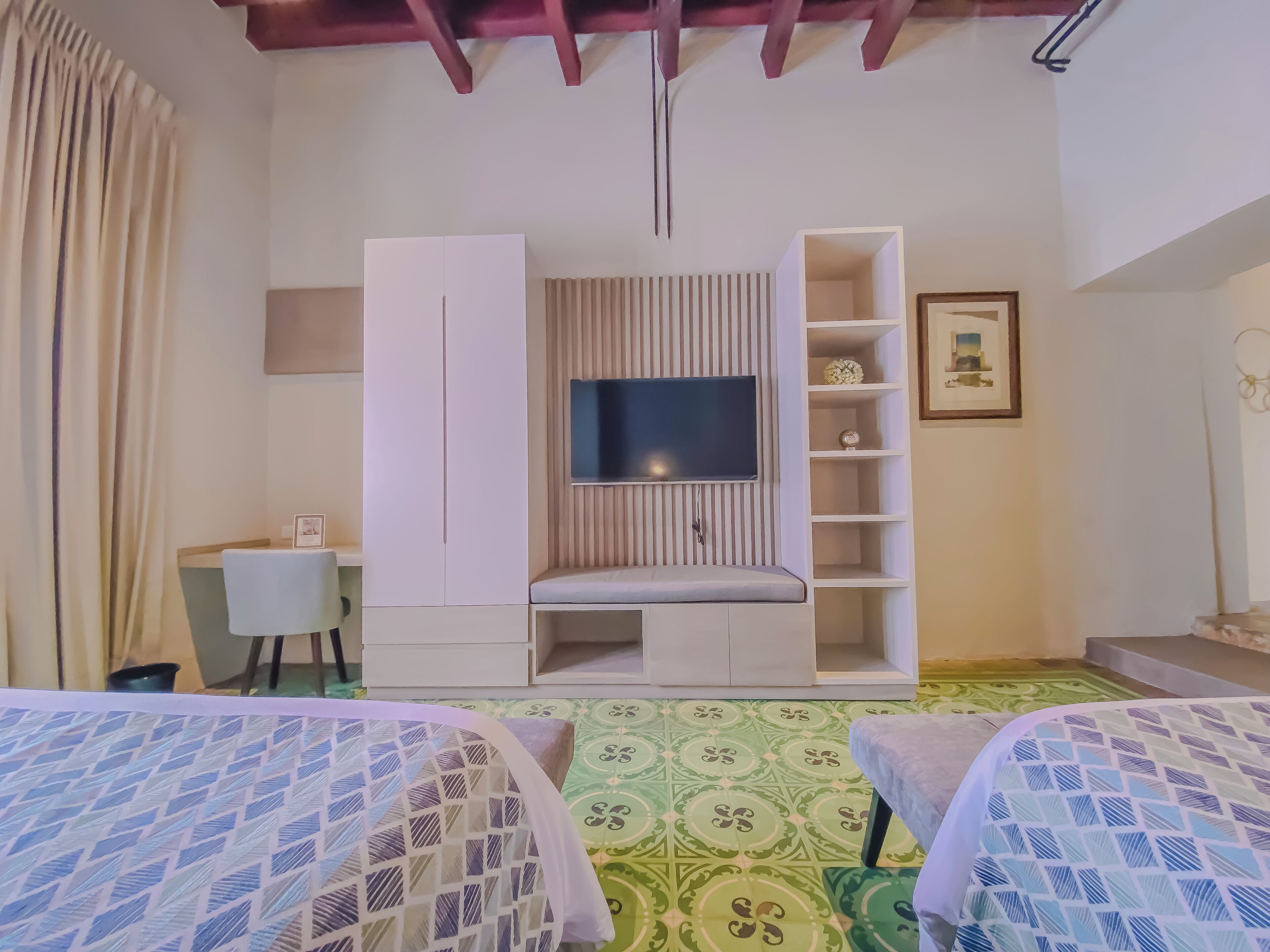 Une chambre avec deux lits, une télévision, un bureau et une armoire.