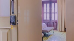 A room with a sliding door, a keypad lock, a bench, and a window with curtains. - Beautiful double suite in an old house with contemporary restoration.  (Heroica Puebla de Zaragoza)