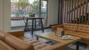 Ein moderner Lounge-Bereich mit Ledersofas, einem Holztisch und Blick auf die Straße durch große Fenster.