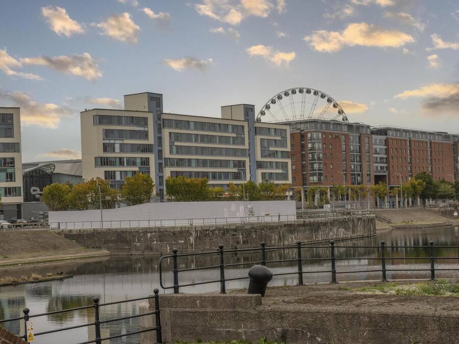 Vista al agua con edificios modernos, una noria y un río.