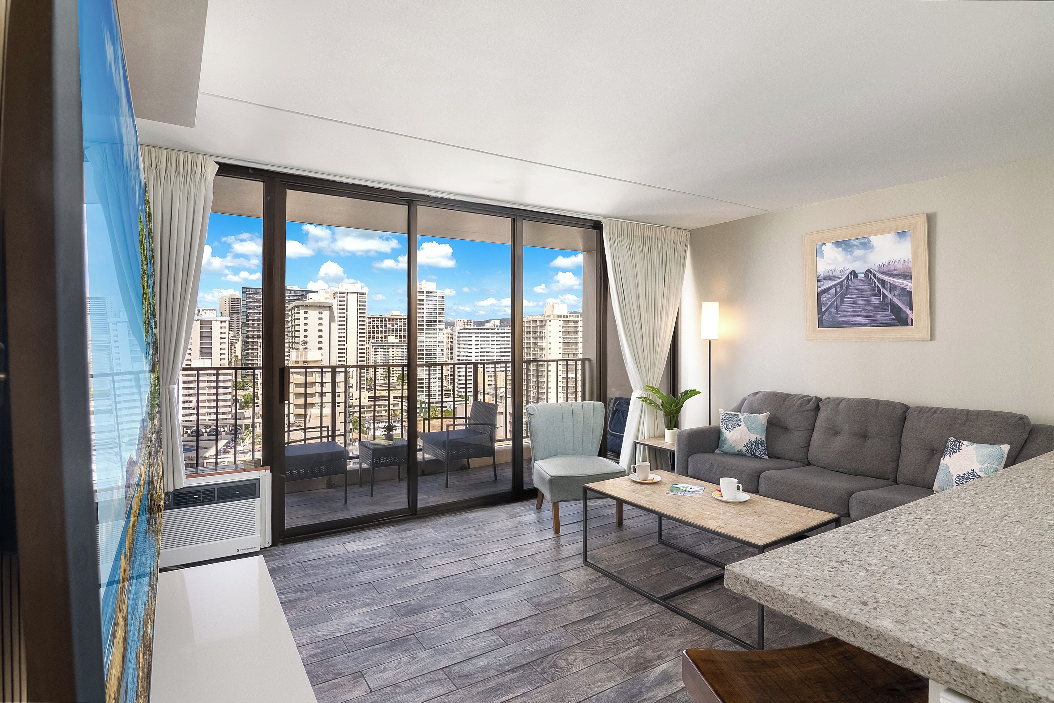 Ein modernes Wohnzimmer mit Blick auf die Stadt, ein graues Sofa, ein Couchtisch und ein Essbereich.