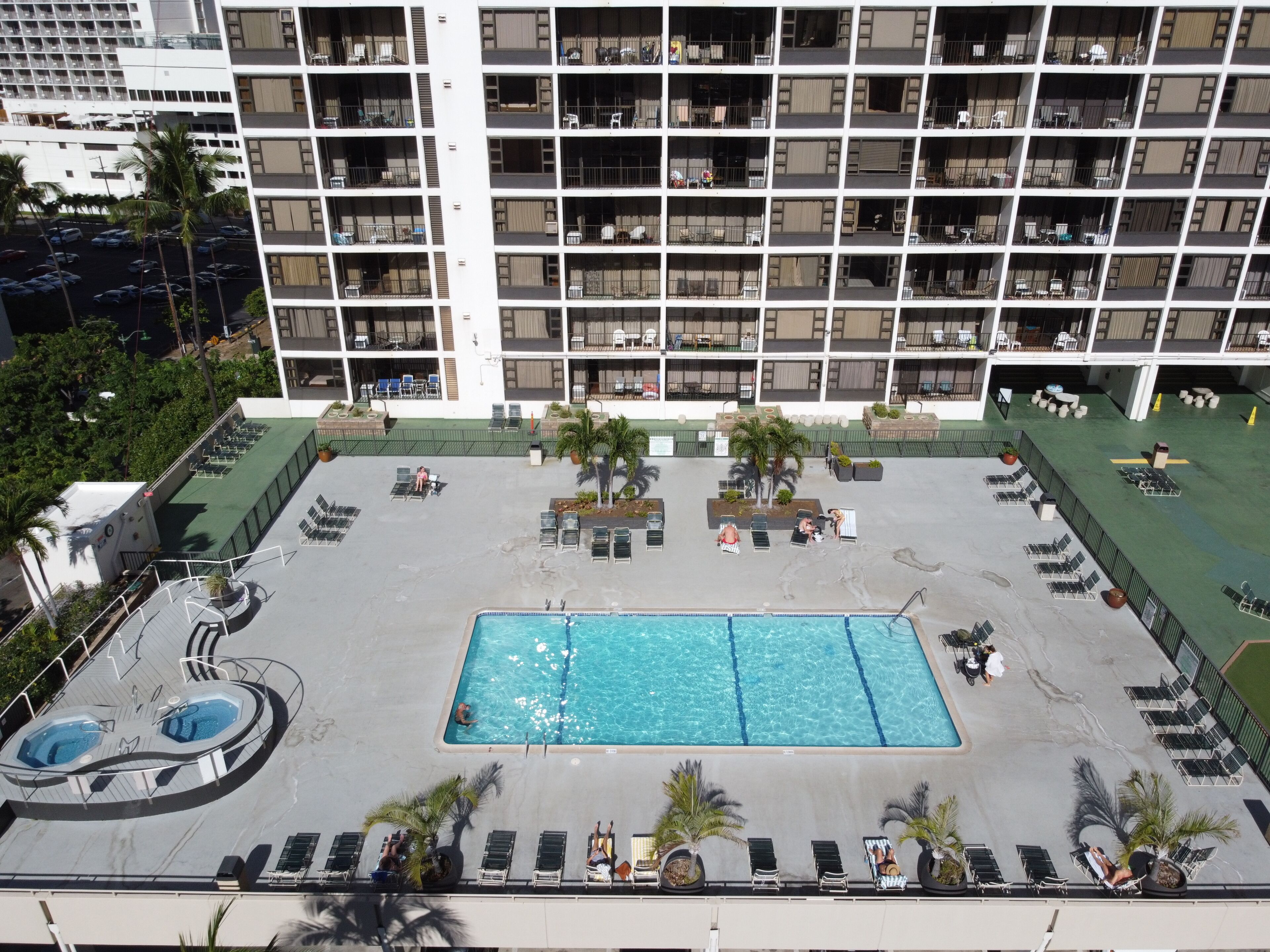 A hotel with a rooftop pool, multiple balconies, and outdoor seating areas.