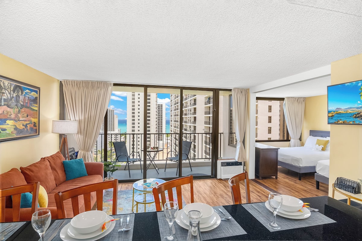 Une chambre d’hôtel avec balcon, un coin repas, un lit et une vue sur les immeubles de grande hauteur.