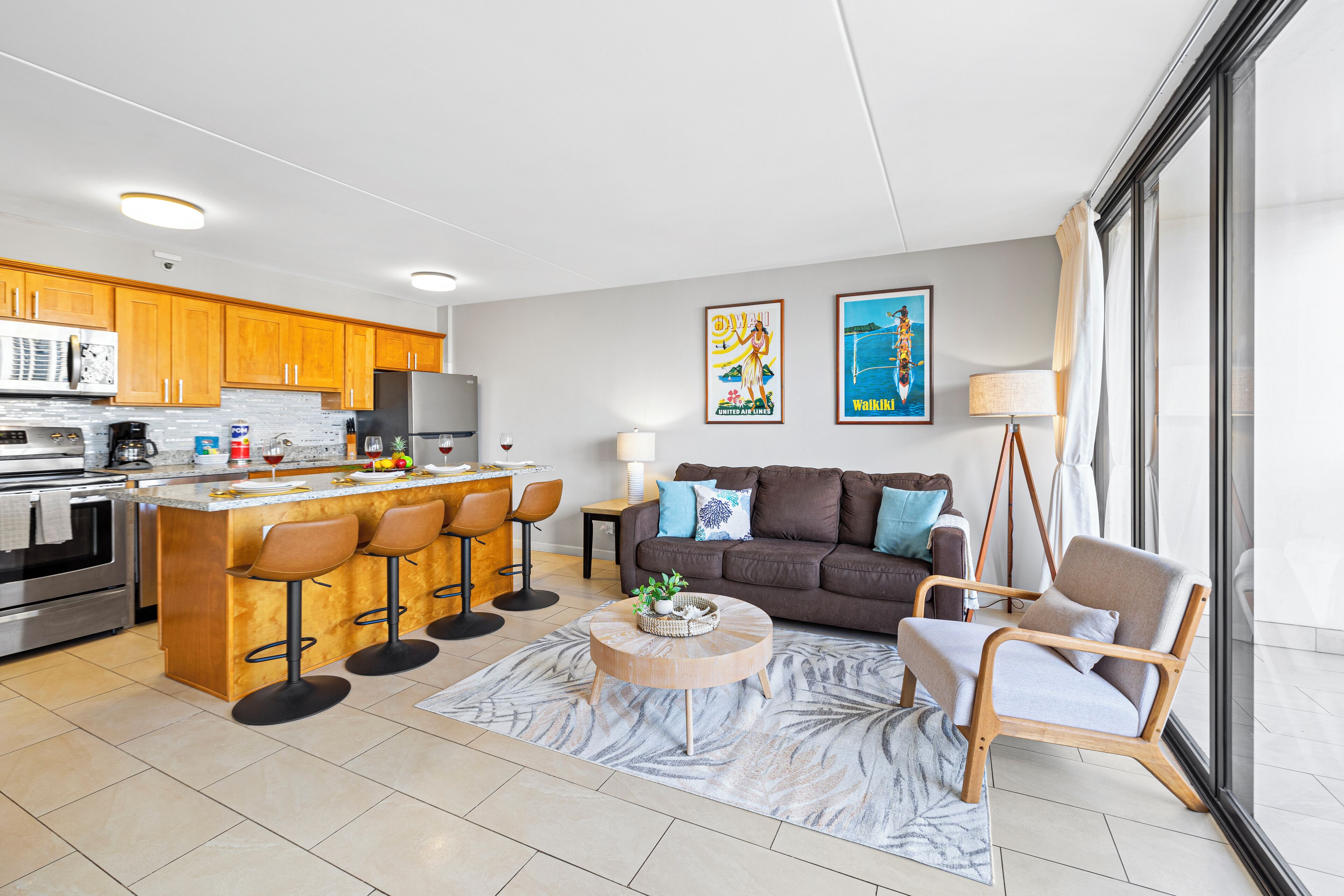 A modern kitchen with a central island, bar stools, a sofa, and a coffee table.