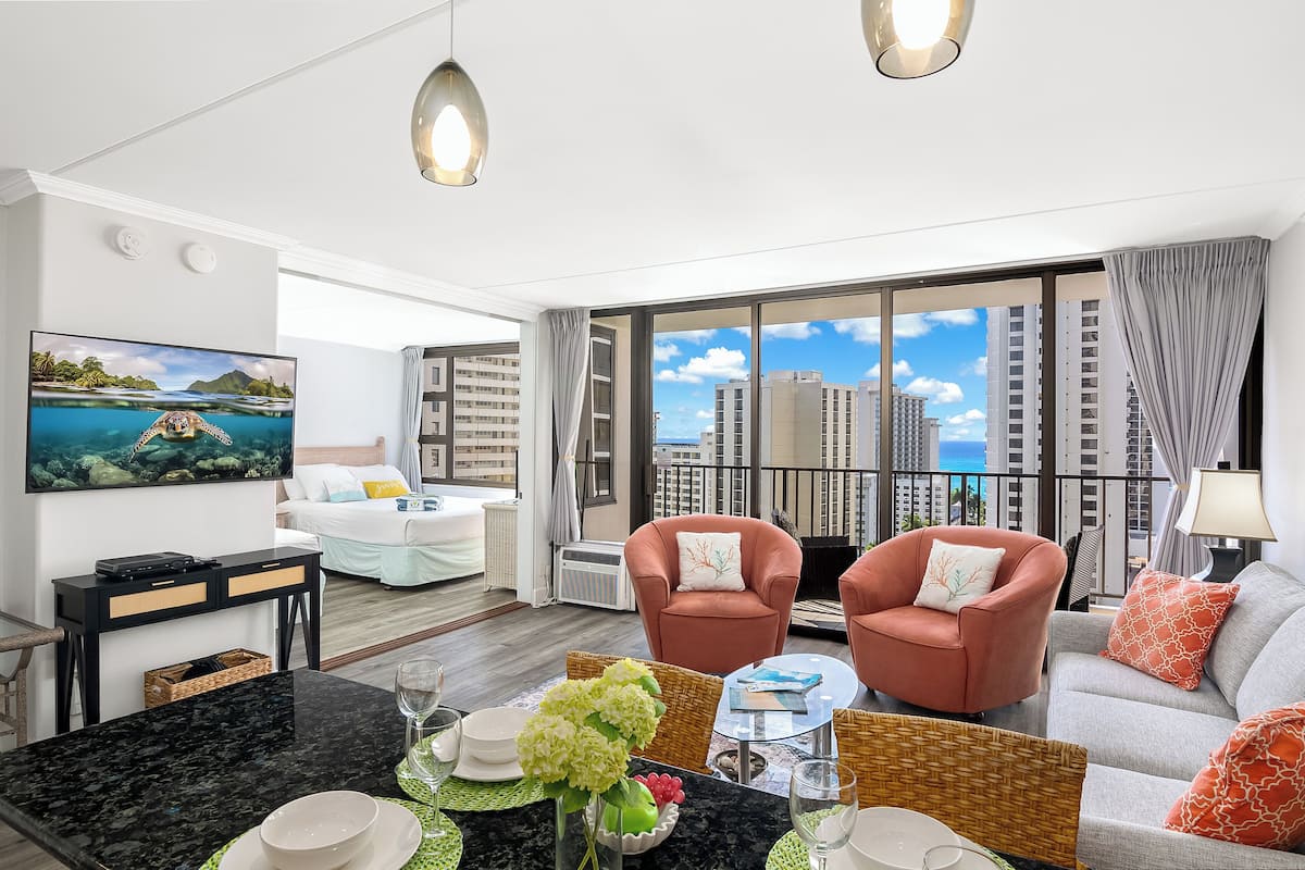 Une chambre d’hôtel moderne dotée d’un balcon, d’une grande télévision et d’un coin repas.