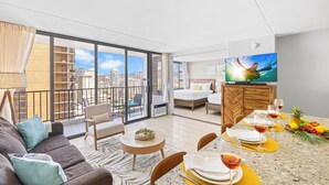 Et moderne hotelværelse med balkon, spiseplads og stort fjernsyn.