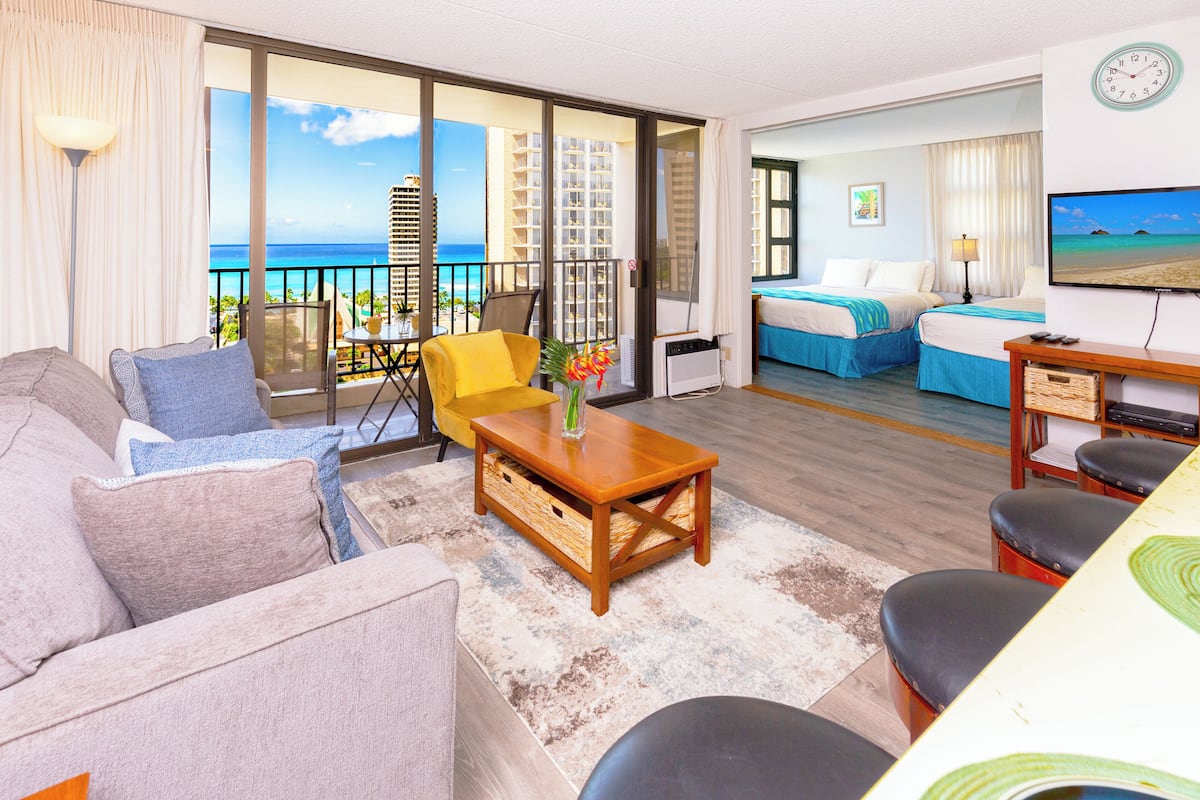 Une chambre d’hôtel avec un balcon, un canapé, une table basse et un lit.
