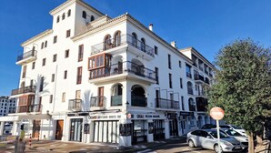 A white building with balconies and a sign for 'OGI Belgian Brasserie'. - Cozy Seaside Apartment in Manilva (Manilva)