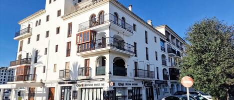 A white building with balconies and a sign for 'OGI Belgian Brasserie'.