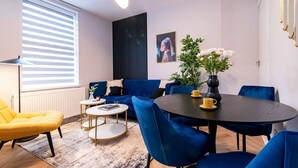 Ein modernes Wohnzimmer mit einem blauen Sofa, einem gelben Sessel und einem runden Esstisch.