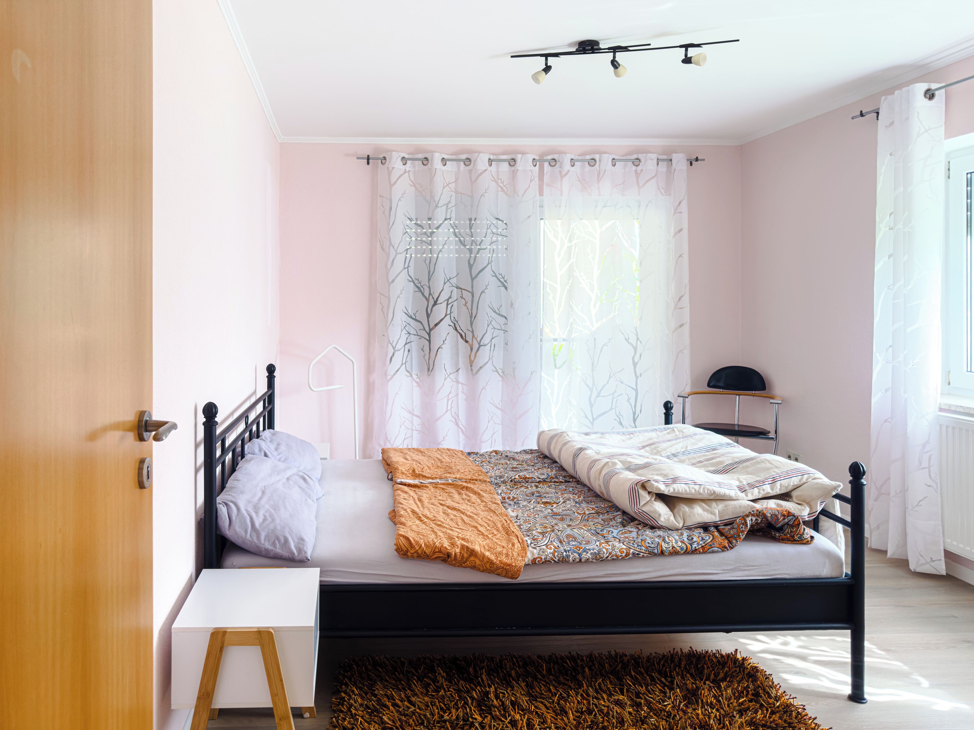 A bedroom with a bed, bedside table, and a chair.