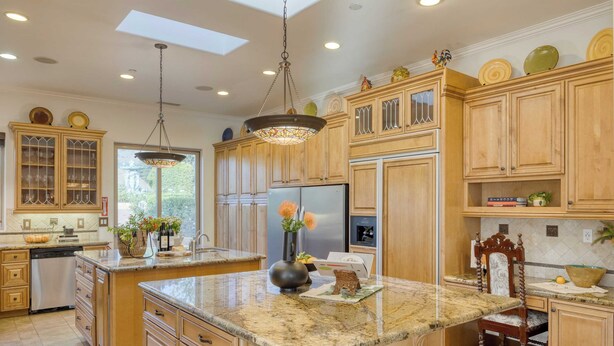 A spacious kitchen with wooden cabinets, granite countertops, and a large island.