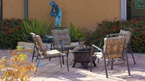 An outdoor seating area with metal chairs and a fire pit.