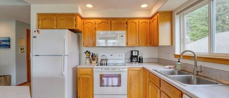 Una cocina con armarios de madera, un refrigerador blanco, un microondas, una estufa y un lavamanos.