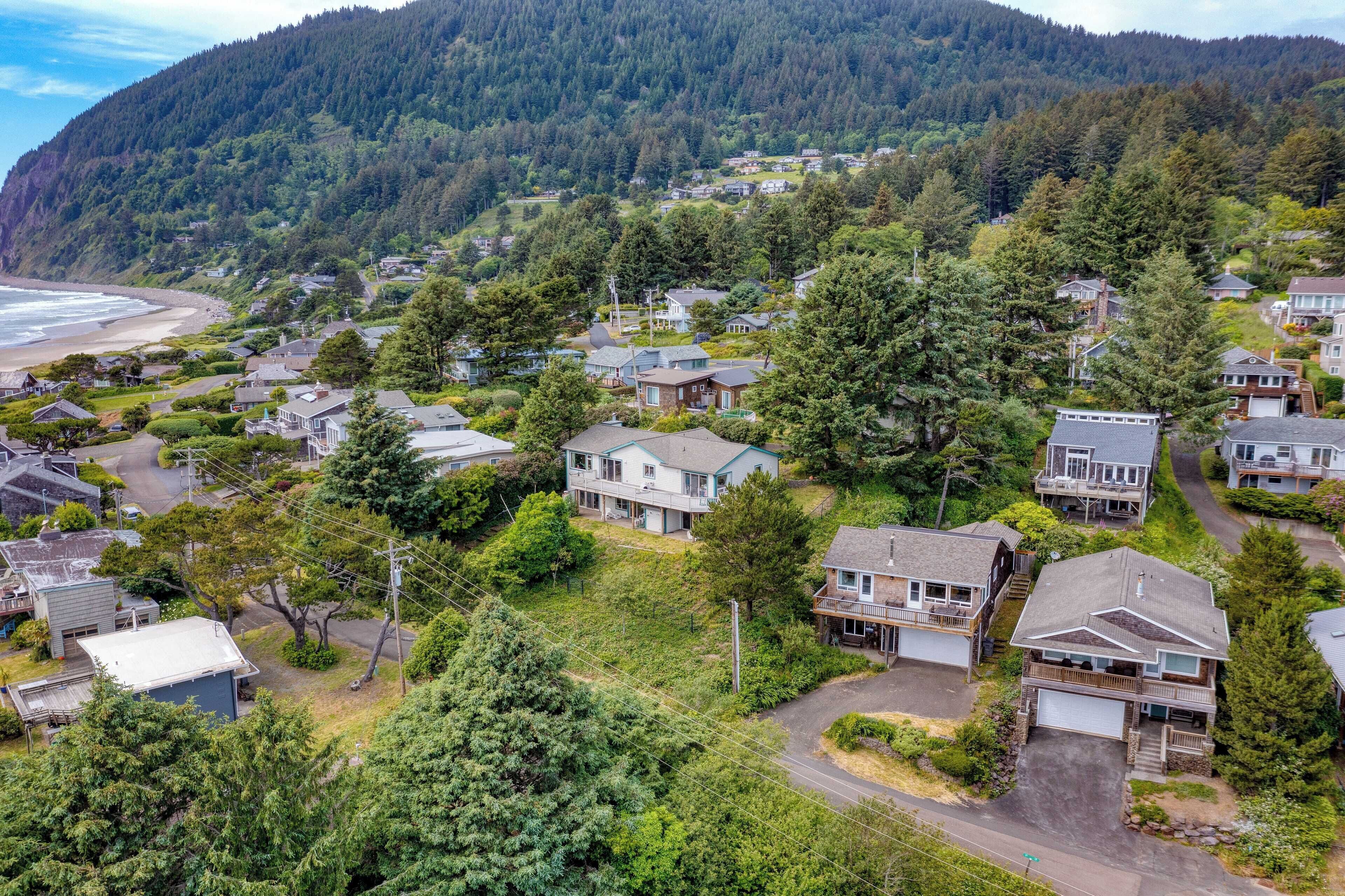 Un quartier résidentiel où les maisons sont entourées d’une forêt dense, avec une plage en arrière-plan.
