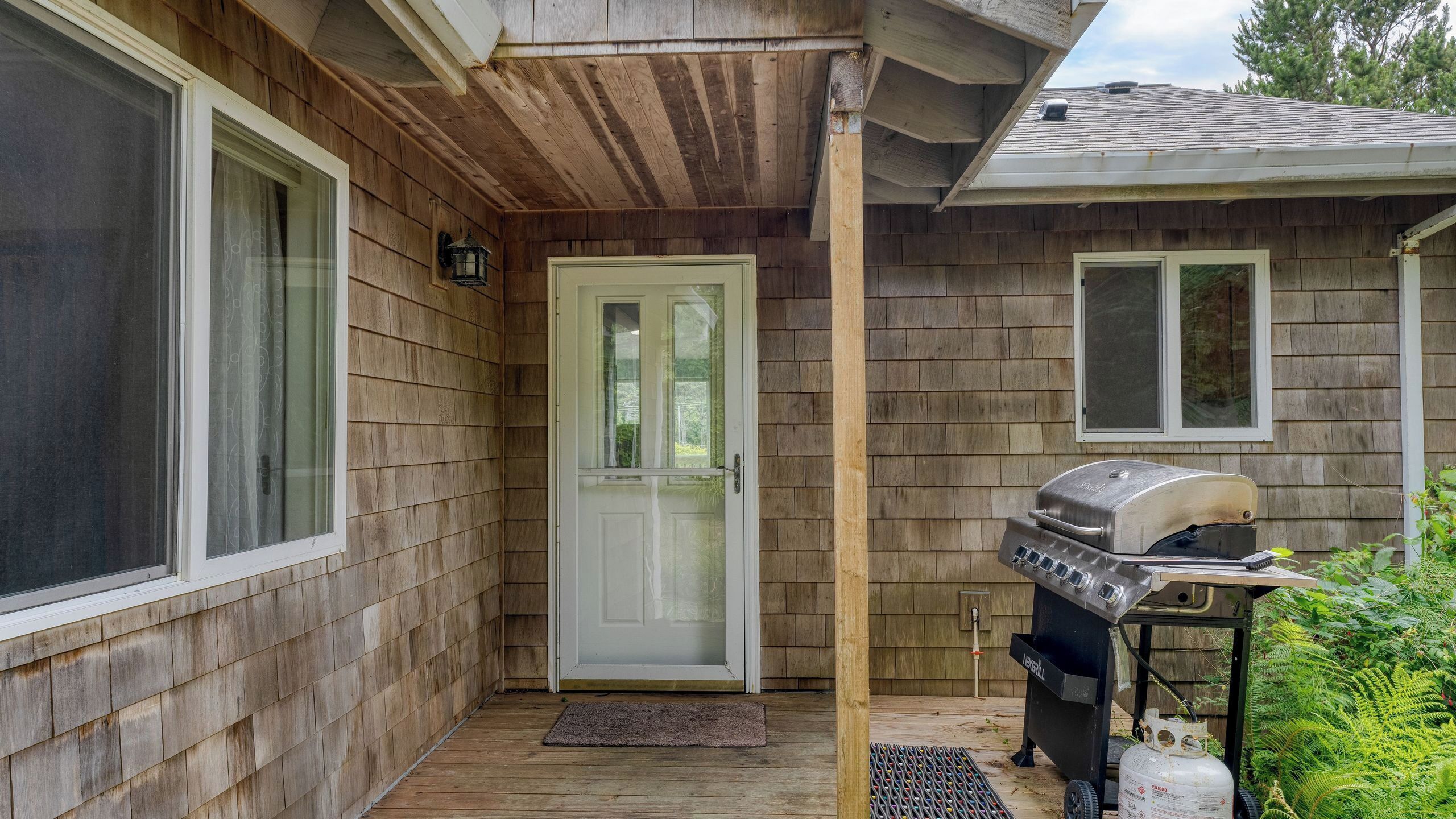 A wooden exterior with a white door, a grill, and a small window.