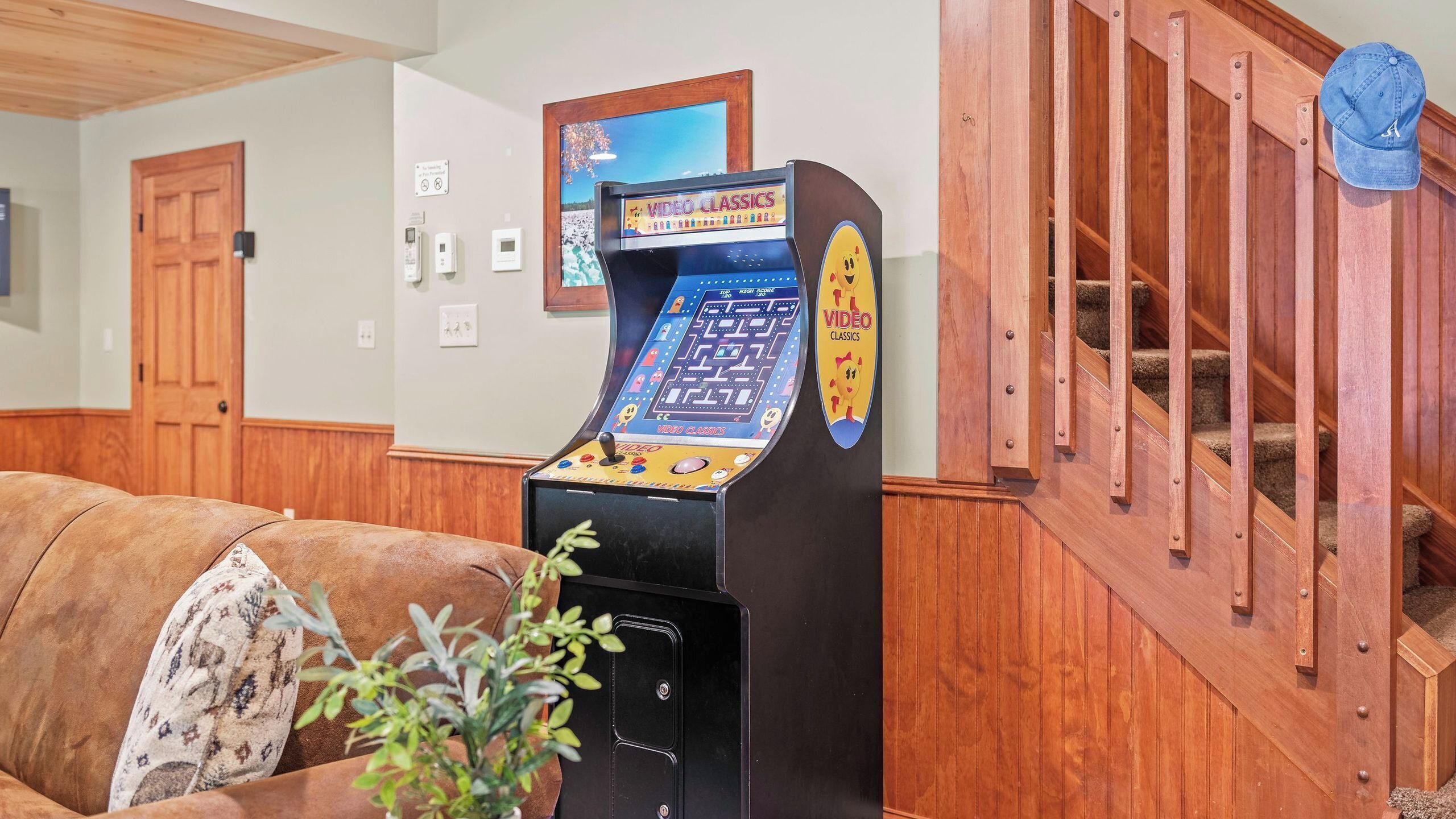 A video game arcade machine labeled 'VIDEO CLASSICS' in a room with wooden paneling and a couch.