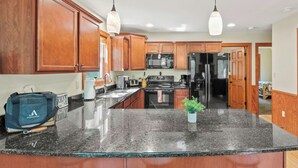 A kitchen with wooden cabinets, a granite countertop, a stainless steel refrigerator, and a microwave.