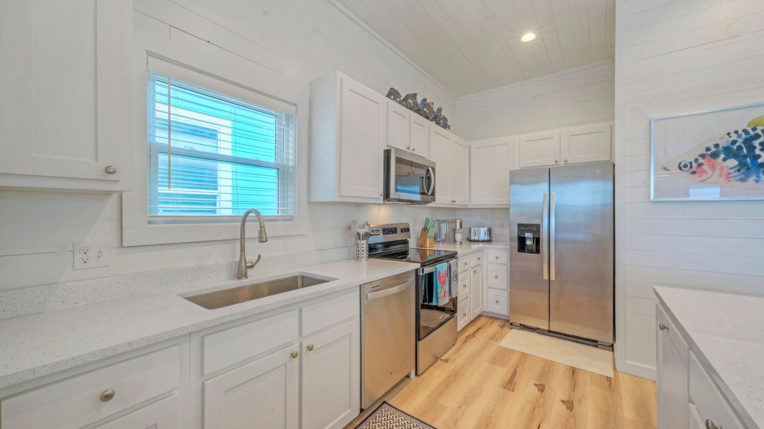 A modern kitchen with white cabinetry, stainless steel appliances, a microwave, and a refrigerator.