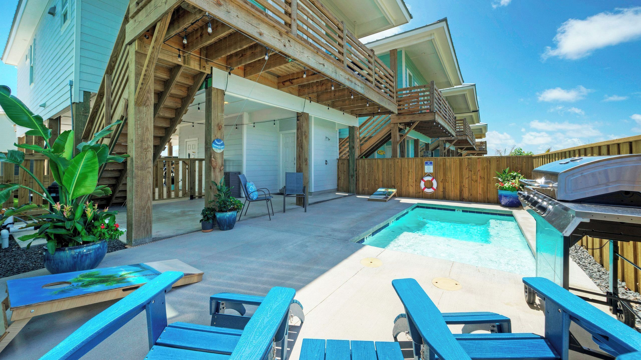 A backyard with a pool, wooden deck, and outdoor seating.