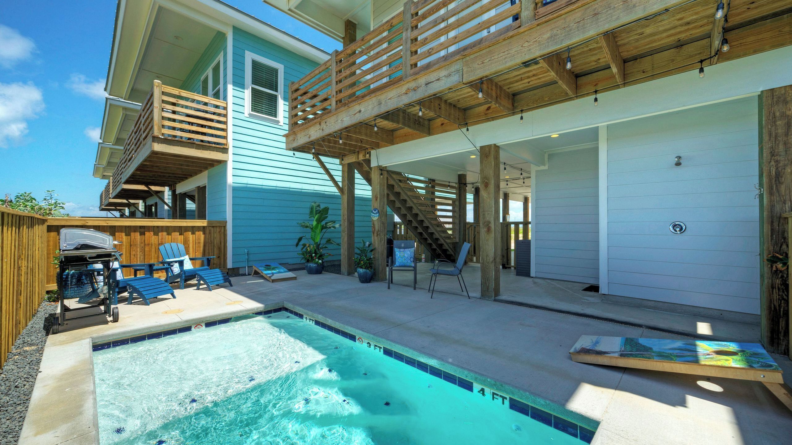 A residential property with a swimming pool, outdoor seating, and a wooden deck.