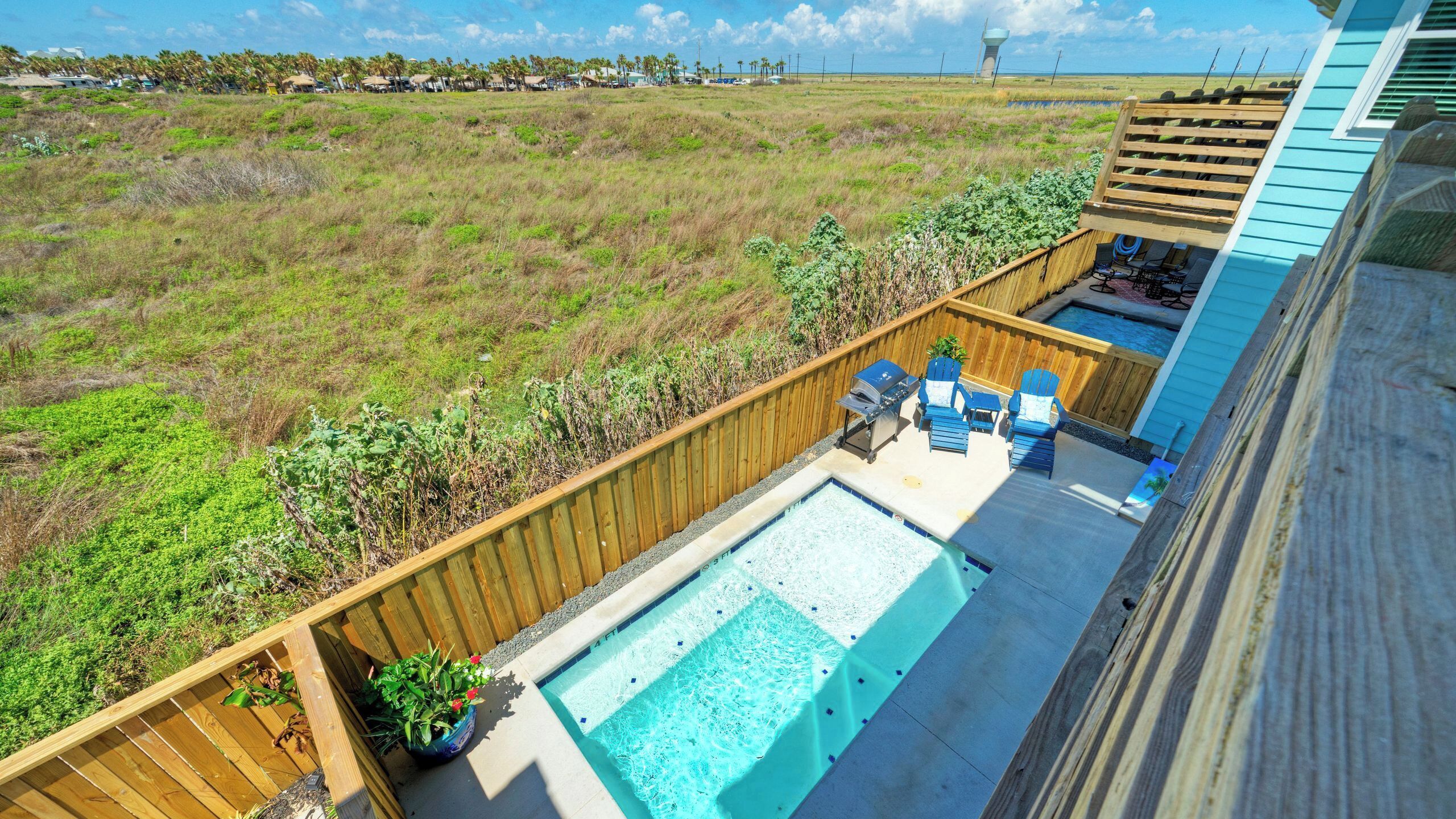 A backyard with a swimming pool, wooden deck, and outdoor seating.