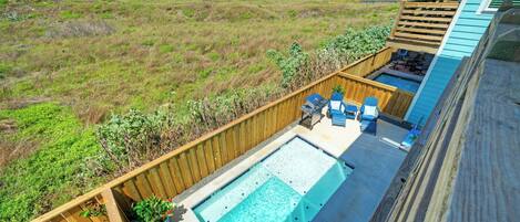 A backyard with a swimming pool, wooden deck, and outdoor seating.