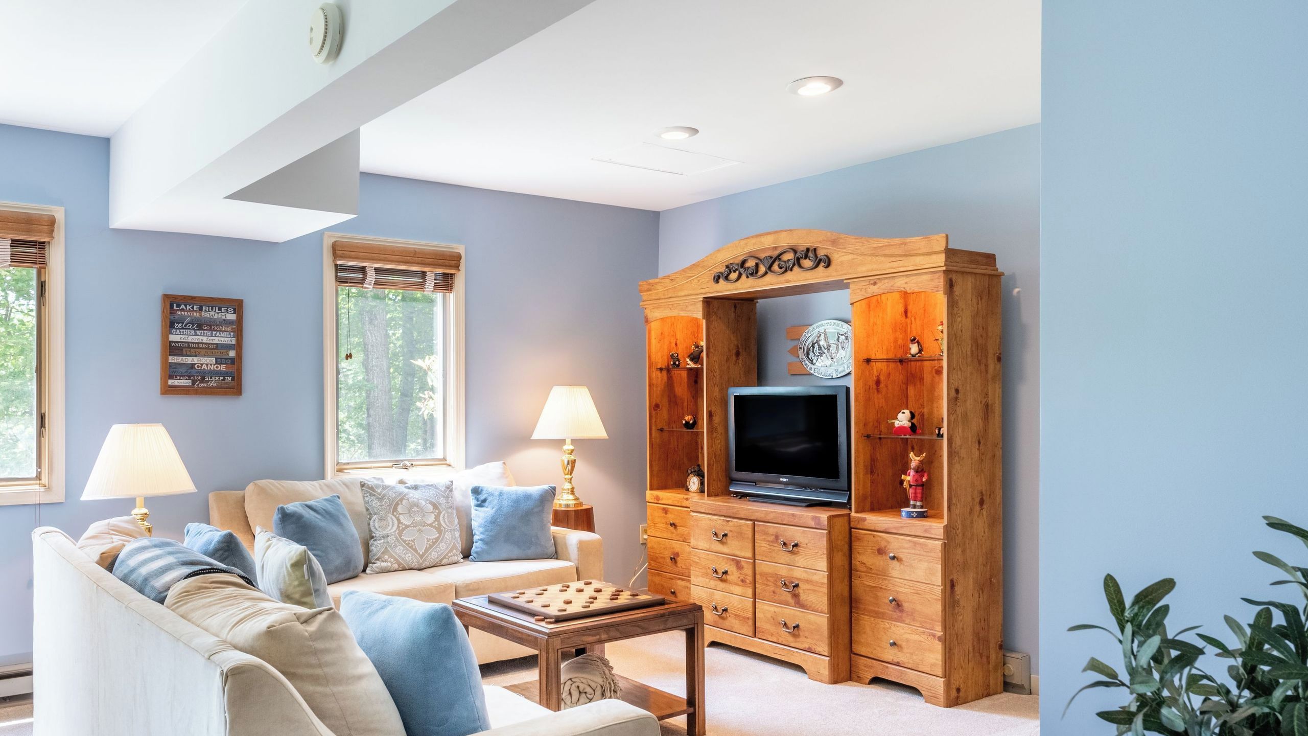 A living room with a sofa, a coffee table, a TV stand with drawers, and a window with blinds.
