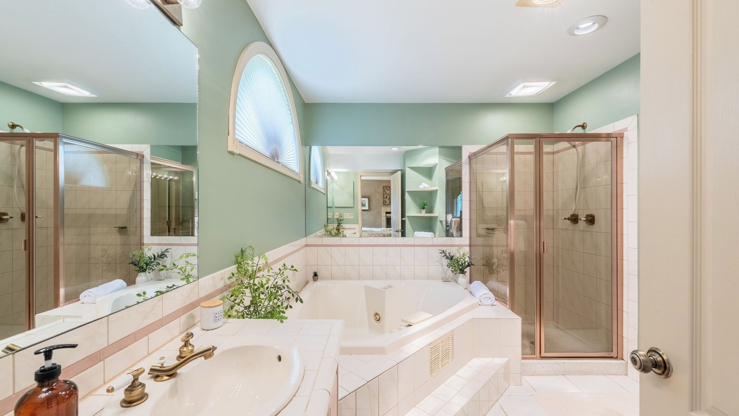 Un baño con un espejo grande, una bañera, una ducha y un lavabo.