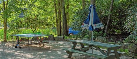 A picnic area with a table and benches, surrounded by trees and rocks.