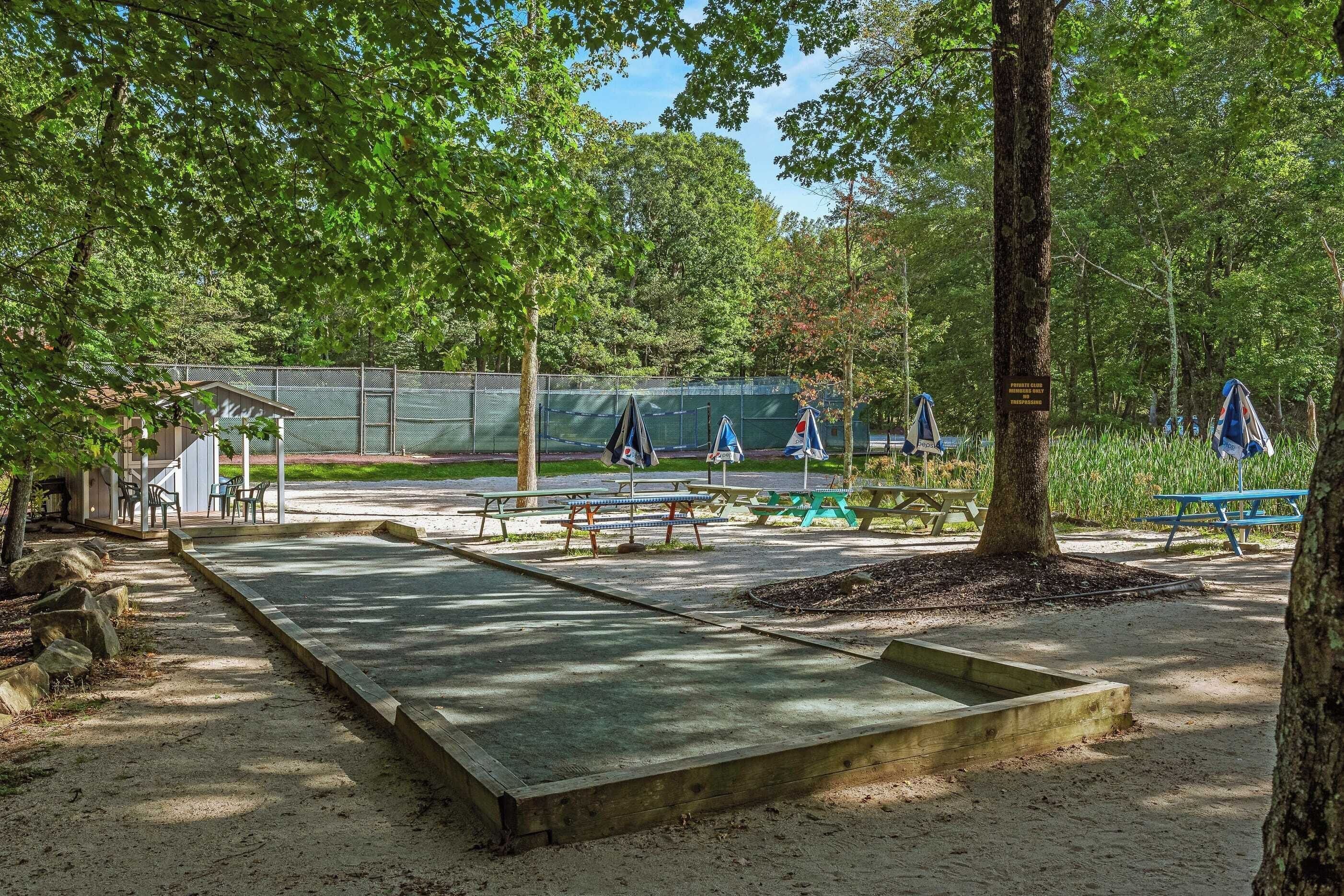 A park with picnic tables, a playground, and a fenced area.
