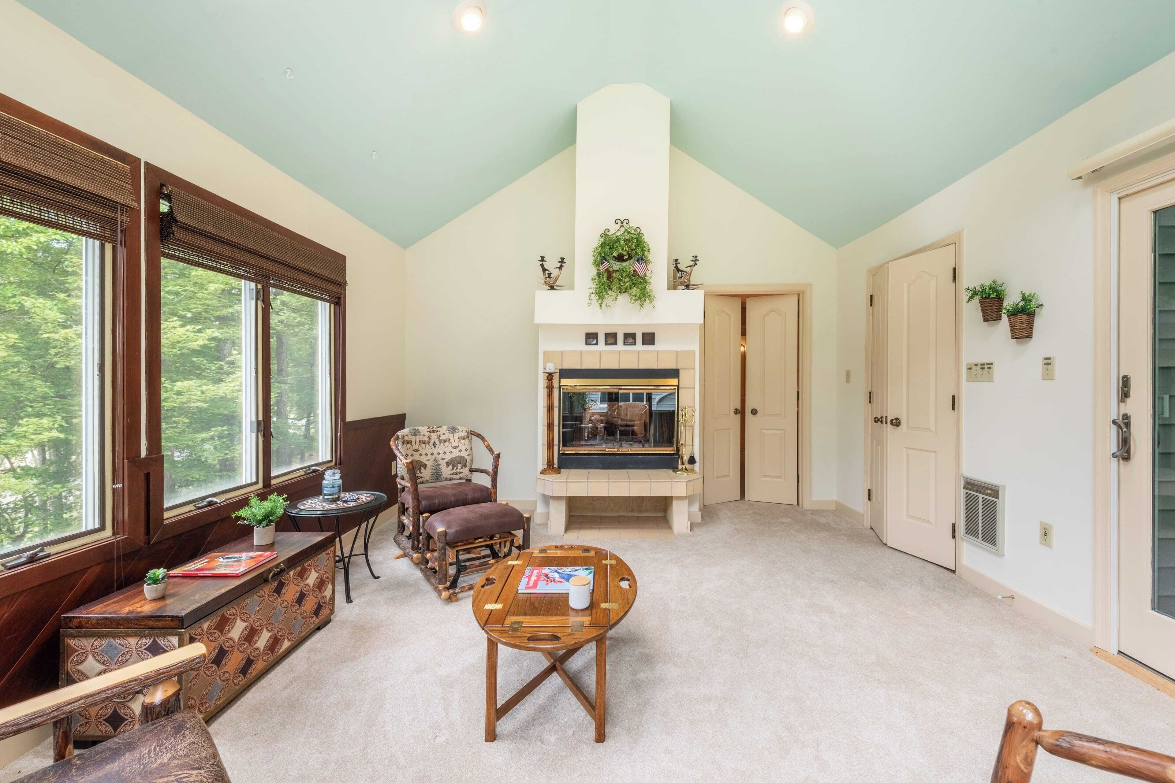 A cozy room with a fireplace, a wooden bench, a round table, and a window with blinds.