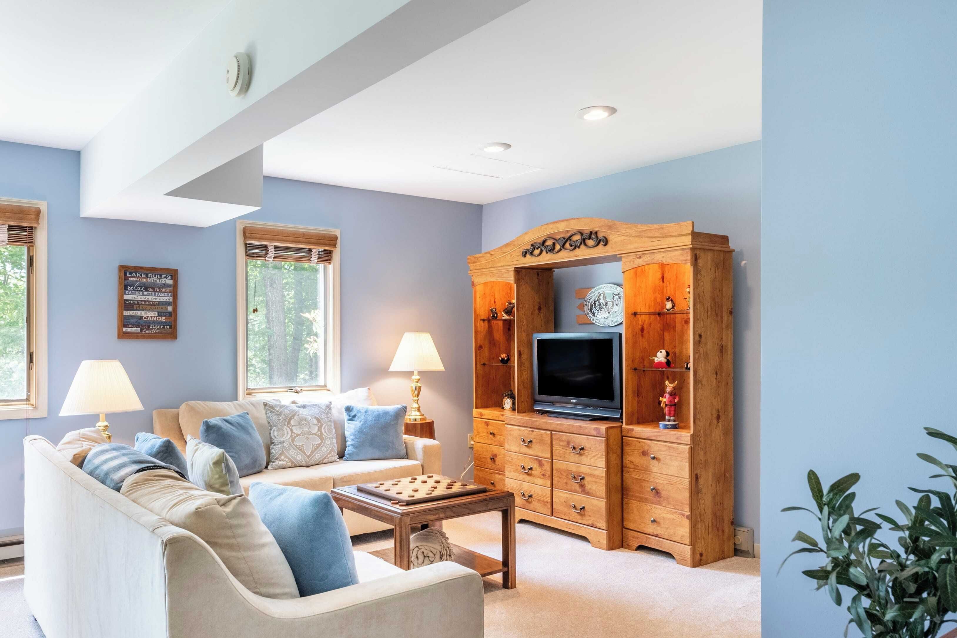 A living room with a beige sofa, a wooden entertainment unit with a TV, and a lamp.