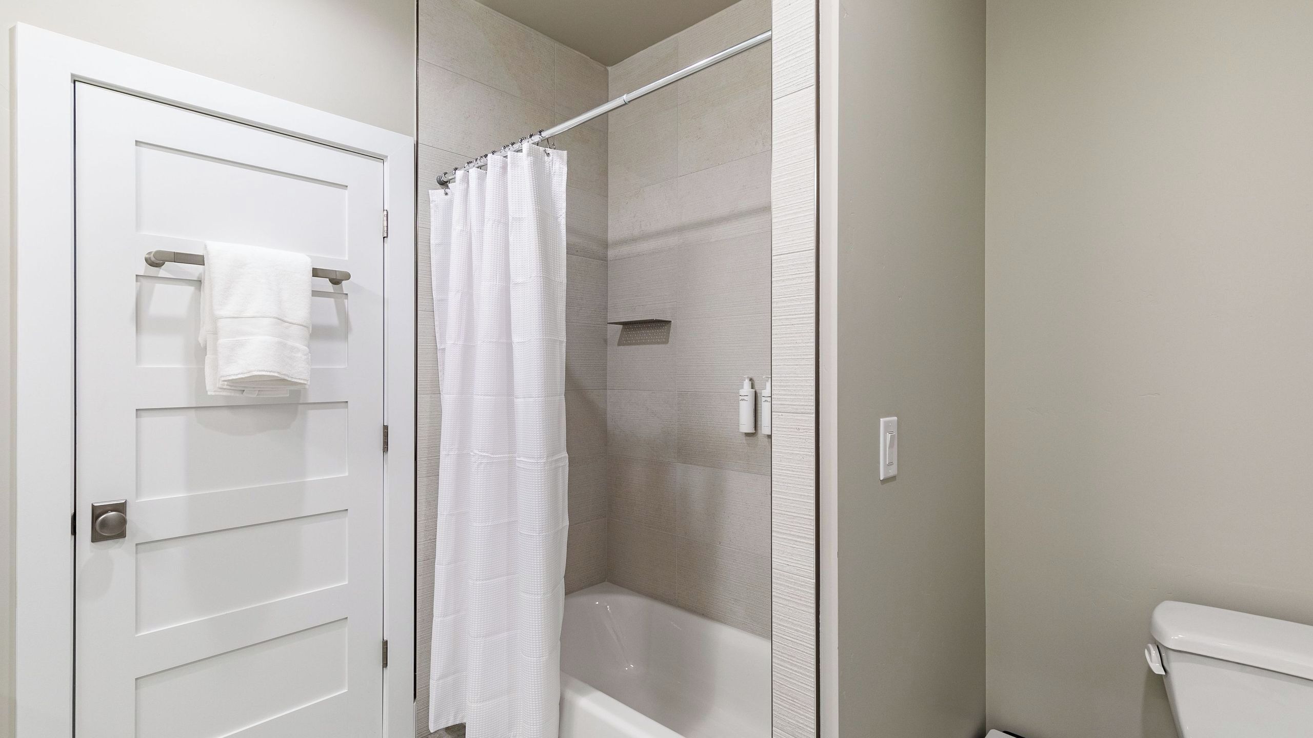 A bathroom with a shower, toilet, and towel rack.
