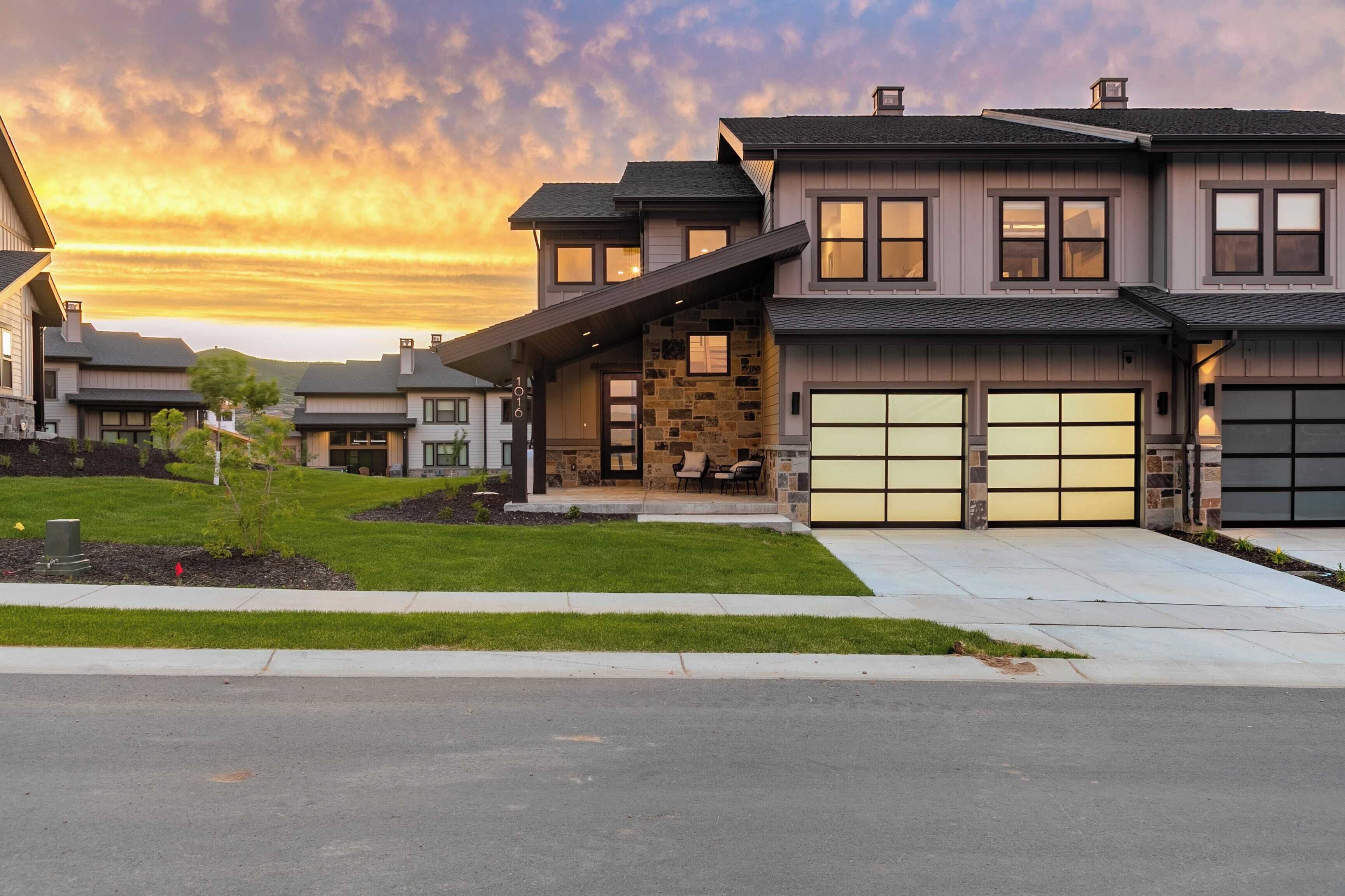 A modern two-story house with a stone facade, a garage, and a well-maintained lawn.
